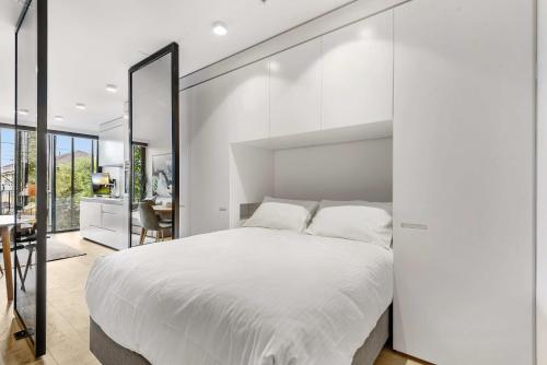 a bedroom with a large white bed with a large mirror at Contemporary 1-Bed in the Heart of St Kilda in Melbourne