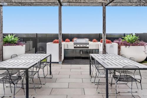 a patio with tables and chairs and a grill at Contemporary 1-Bed in the Heart of St Kilda in Melbourne