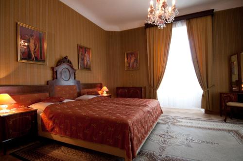 a bedroom with a large bed and a chandelier at Schlosshotel Zamek Zdikov in Zdíkov