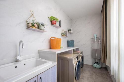 a bathroom with a sink and a washing machine at Jinjiang Inn Select Heze Wanxiang Plaza Guiling Road in Zhaolou