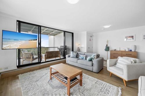 una sala de estar con un sofá y una mesa en Beachside 3-Bed with BBQ, Pool, Gym & Tennis Court, en Marcoola