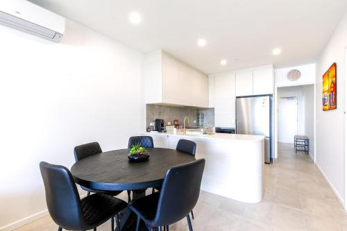 a kitchen with a black table and chairs and a refrigerator at Glorious 2-Bed with Waterside Balcony Views in Batemans Bay