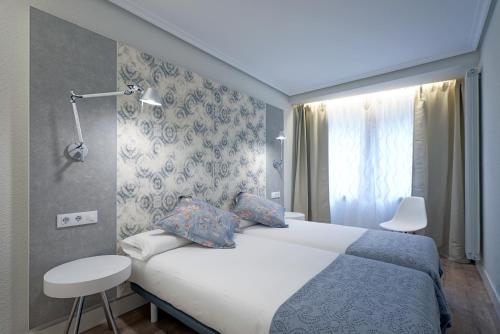 ein Hotelzimmer mit einem Bett und einem Fenster in der Unterkunft Apartamento Zurriola Luxury - Surf Beach con aire acondicionado in San Sebastián