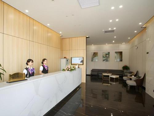 zwei Frauen stehen an einem Tresen im Wartezimmer in der Unterkunft Green Tree Inn Express Yulin Chinese Medicine Port in Yulin