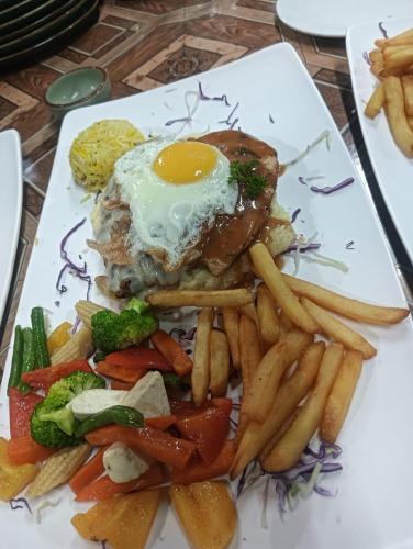 un piatto di cibo con un uovo e patatine fritte di Nirvana Beach Cottages a Canacona