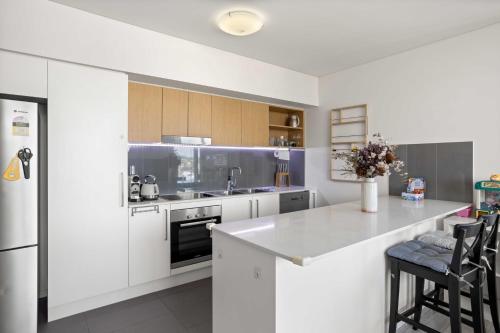 a kitchen with white cabinets and a kitchen island at Spaciously Bright 1-Bed Apartment in Brisbane
