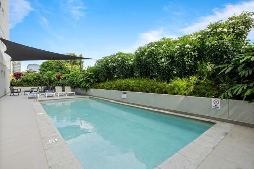 a swimming pool with chairs and plants on a building at Spaciously Bright 1-Bed Apartment in Brisbane