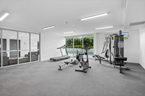 a gym with several treadmills and machines in a room at Spaciously Bright 1-Bed Apartment in Brisbane