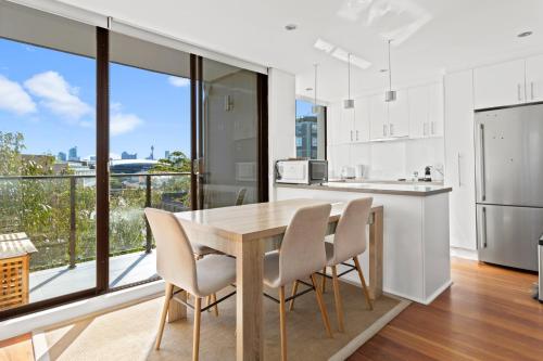 a kitchen with a wooden table and chairs and a large window at Prime Location 2-Bed Apartment with Parking in Sydney