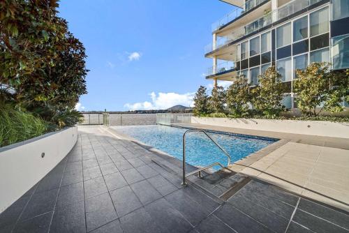 a swimming pool in front of a building at Canberra Lakefront 2-Bed with Pool, Gym & Parking in Kingston