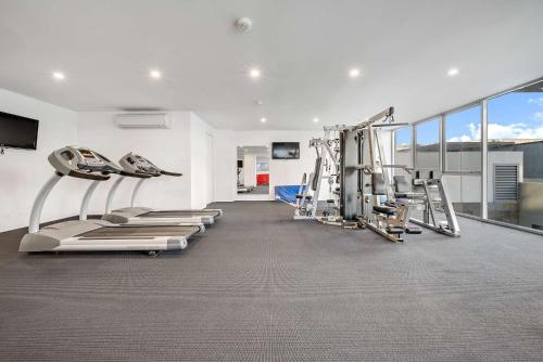 a gym with treadmills and machines in a room at Canberra Lakefront 2-Bed with Pool, Gym & Parking in Kingston