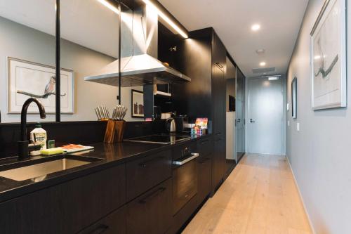 a kitchen with black cabinets and a sink at Stunning 1-Bed Above Foreshore with Water Views in Kingston