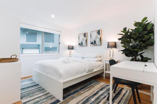ein weißes Schlafzimmer mit einem weißen Bett und einem Schreibtisch in der Unterkunft Lakeside 3-Bed Apartment with Jacuzzi in Belconnen