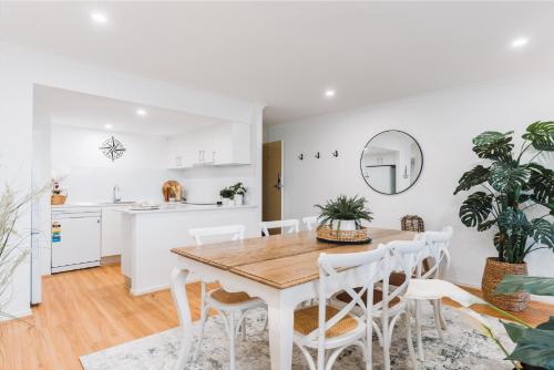 eine Küche und ein Esszimmer mit einem Holztisch und Stühlen in der Unterkunft Lakeside 3-Bed Apartment with Jacuzzi in Belconnen