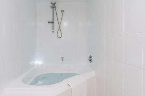 a white bathroom with a tub in the corner at Lakeside 3-Bed Apartment with Jacuzzi in Belconnen