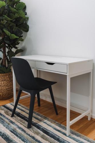 a white desk with a black chair next to a rug at Lakeside 3-Bed Apartment with Jacuzzi in Belconnen