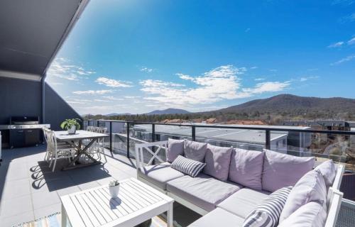 a balcony with a couch and a table with a view at Mountain View City Center Apartment with BBQ in Canberra