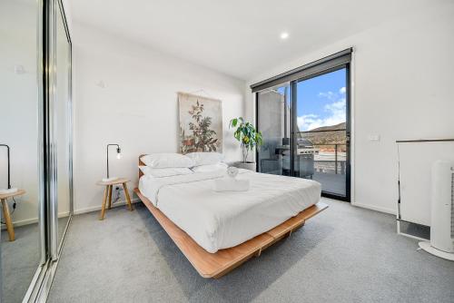 a bedroom with a bed and a large window at Mountain View City Center Apartment with BBQ in Canberra