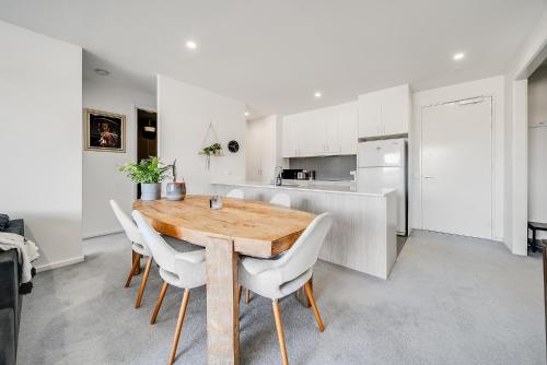 a kitchen and dining room with a wooden table and chairs at Mountain View City Center Apartment with BBQ in Canberra