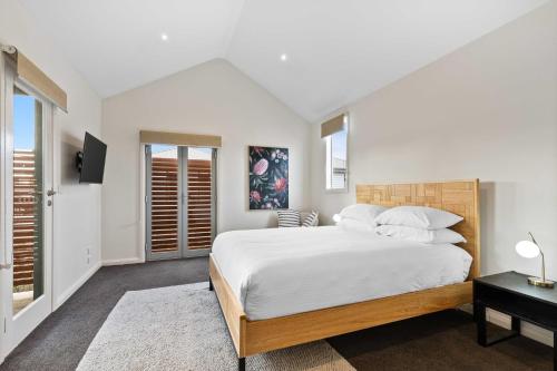 a white bedroom with a large bed and windows at Chic 2-Bed Home By Bustling Shops in Yarraville