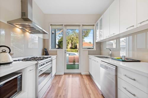 a kitchen with white cabinets and a stove top oven at Chic 2-Bed Home By Bustling Shops in Yarraville
