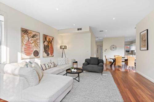 a living room with a white couch and a table at Chic 2-Bed Home By Bustling Shops in Yarraville