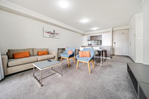 a living room with a couch and chairs and a table at Comfy 2-Bed Near the Lake with Secure Parking in Tuggeranong