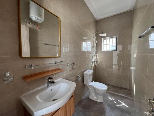 Un baño con lavabo, inodoro y espejo. en TAF City Home, en Sifoe