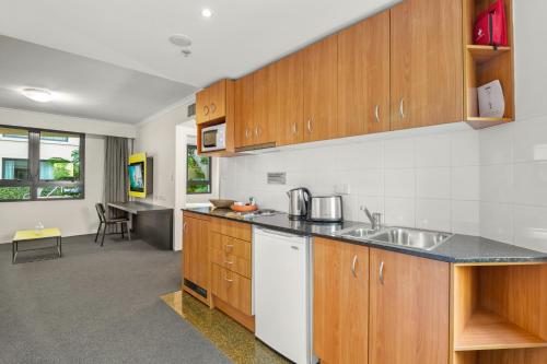 a kitchen with wooden cabinets and a counter top at Contemporary 1-Bed First Floor Unit with Pool in Sydney