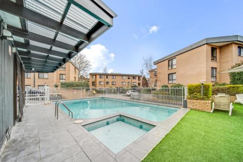 a swimming pool in a yard next to a building at 2-Bed with Pool, BBQ, Tennis Court & Parking in Kingston