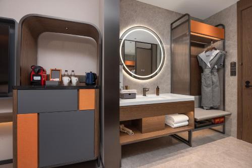 un bagno con lavandino e specchio di UrCove by Hyatt Xi'an Bell Tower Huimin Street Hotel a Xi'an
