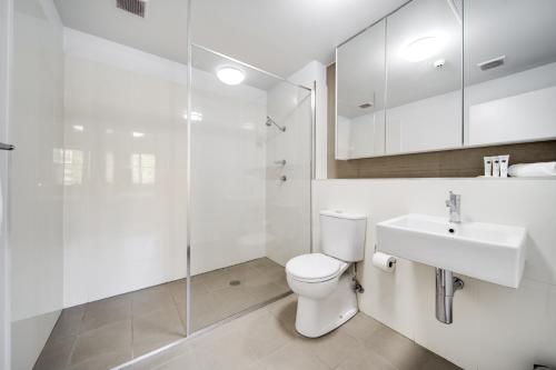 a bathroom with a toilet and a sink and a shower at Spacious 2-Bed Conveniently by Lake Tuggeranong in Tuggeranong