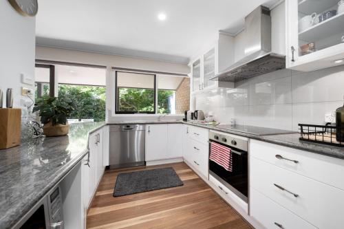 Una cocina con gabinetes blancos y una bandera estadounidense en la estufa. en Gorgeous 2-Bed Townhouse with Patio, BBQ & Parking, en Kingston 