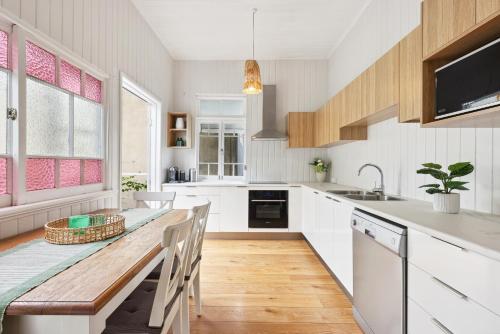 a kitchen with white cabinets and a wooden table at Tranquil 3-Bed Family Home with Spacious Backyard in Brisbane