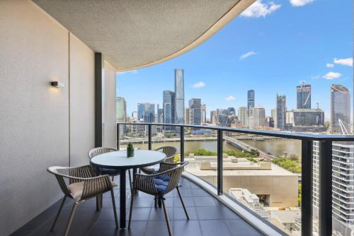 a balcony with a table and chairs and a view of the city at Chic 2-Bed with Rooftop Pool Overlooking the City in Brisbane