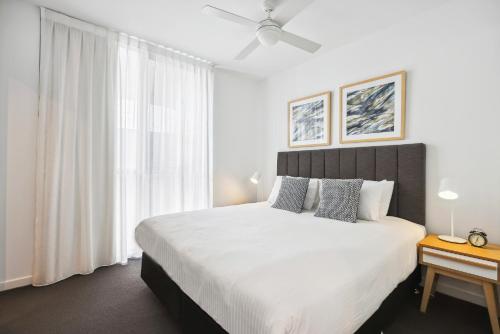 a white bedroom with a large bed and a window at Chic 2-Bed with Rooftop Pool Overlooking the City in Brisbane