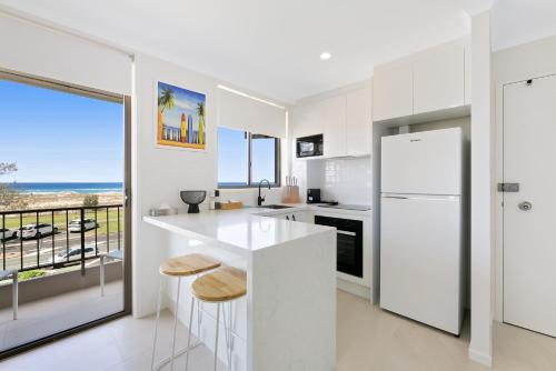 a white kitchen with a view of the ocean at Beachfront Studio with Balcony & Stunning Views in Gold Coast