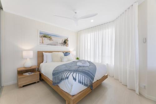 a white bedroom with a bed and a window at Beachfront Studio with Balcony & Stunning Views in Gold Coast