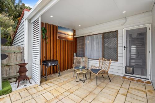 - une terrasse avec 2 chaises, une table et un grill dans l'établissement Chic 2-Bed Cabin-Style Home by Mooloolaba Beach, à Mooloolaba