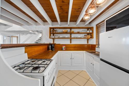 a kitchen with white appliances and wooden ceilings at Chic 2-Bed Cabin-Style Home by Mooloolaba Beach in Mooloolaba