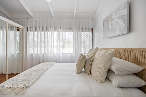 a bedroom with a white bed with pillows and a window at Chic 2-Bed Cabin-Style Home by Mooloolaba Beach in Mooloolaba