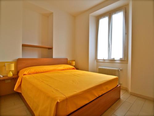 ein Schlafzimmer mit einem Bett mit einer orangefarbenen Tagesdecke und einem Fenster in der Unterkunft Locanda Posta in Argegno
