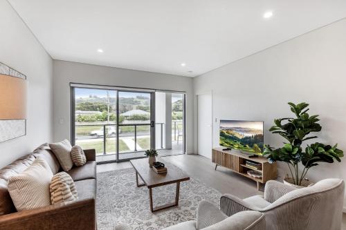 a living room with a couch and a tv at First Floor 3-Bed Stunning Unit by The Ocean in Kiama