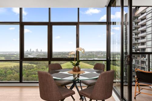 a dining room with a table and chairs and large windows at Chic 1-Bed with Pool by River Ferry & Amenities in Sydney
