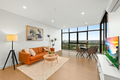 a living room with an orange couch and a table at Chic 1-Bed with Pool by River Ferry & Amenities in Sydney