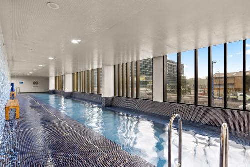 a large swimming pool in a building with windows at Chic 1-Bed with Pool by River Ferry & Amenities in Sydney