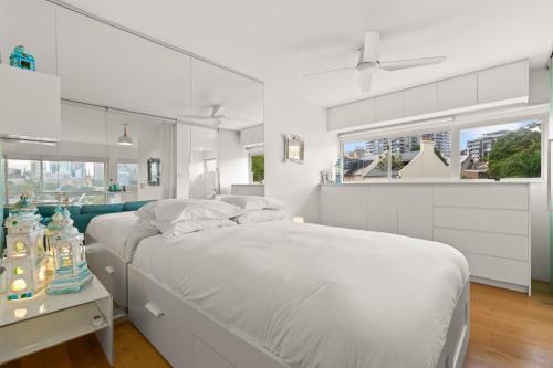 a white bedroom with a bed and a window at Cosy 1-Bed with Swimming Pool Facing Opera House in Sydney