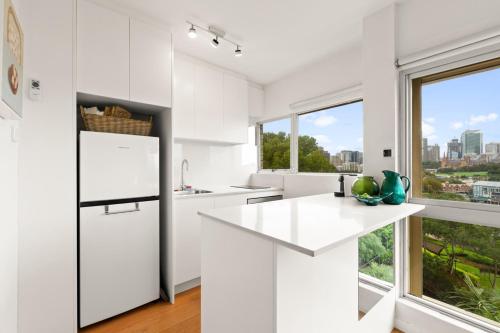 a kitchen with white cabinets and a large window at Cosy 1-Bed with Swimming Pool Facing Opera House in Sydney