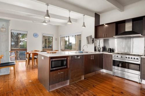 a large kitchen with wooden cabinets and a table at Spacious 4-Bed Home 5-min from the Beach in Capel Sound