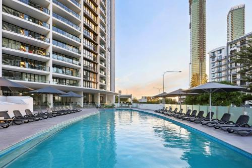 a swimming pool with chairs and umbrellas and buildings at Ocean View 3-Bed with Gym, Pool, Sauna & Parking in Gold Coast